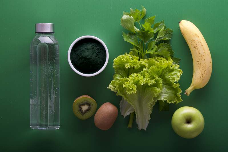 Dietitian writing notes beside a table featuring gut-friendly ingredients: oats, chia seeds, yogurt, garlic, and kale